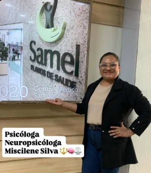 Miscilene Silva em frente ao letreiro do centro de saúde onde atende, identificada como Psicóloga Neuropsicóloga